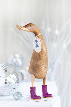 a wooden duck with purple boots standing on top of a table