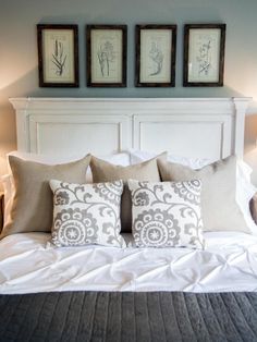 a bed with two framed pictures on the wall above it and three lamps at the headboard