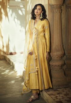 Editor's Note The Vintage Matsya Angrakha Farshi Kalidar in Sunflower is crafted from handloom Chanderi with Resham Ari and Zardoze embroidery, paired with straight, comfortable pants and a monotone handcrafted organza dupatta. The Farshi Anarkali features exquisite handwork on the Angrakha neck and sleeves. The monotone dupatta is enhanced with shining embroidery and tassels hanging in the corners. Fabric: Chanderi silk Color: Yellow Disclaimer: Product colour may slightly vary due to photograp Angarkha Anarkali, Angrakha Anarkali, Yellow Anarkali, Silk Kurta, Organza Dupatta, Embroidered Neckline, Indian Fashion Designers, Fashion App, Kurta Set