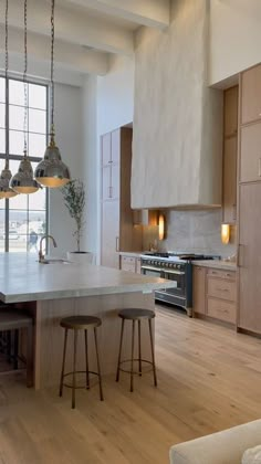 a large kitchen with an island and stools in front of the stove top oven