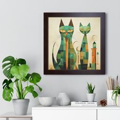 two green cats sitting next to each other on a white shelf in front of a potted plant