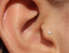 a woman's ear with a single diamond in it