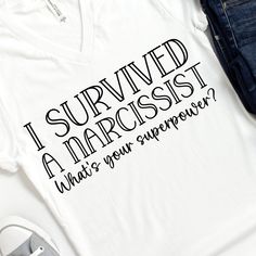 a white t - shirt with the words i survived in black ink on it next to a pair of jeans