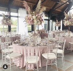 the tables are set with white chairs and pink tablecloths for an elegant wedding reception