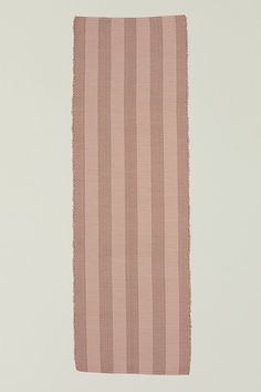 a pink and brown striped rug on a white wall