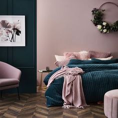 a bedroom with purple walls and green bedding, pink chair, and rug on the floor