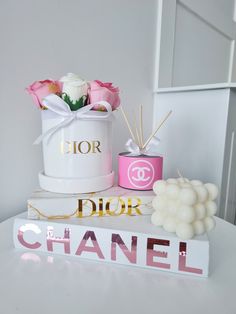 a table topped with a white bucket filled with flowers and candles next to a sign that says dior