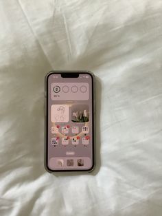 an iphone sitting on top of a bed covered in white sheets and paper stickers