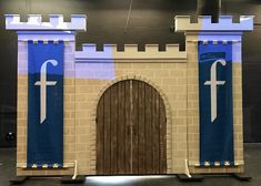 an entrance to a castle made out of cardboard with blue and white flags on it