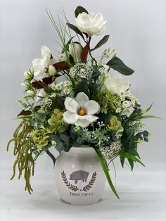 a vase filled with white flowers and greenery