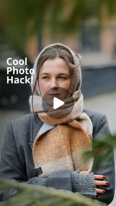 a woman with a scarf around her head is looking at the camera while wearing a gray coat