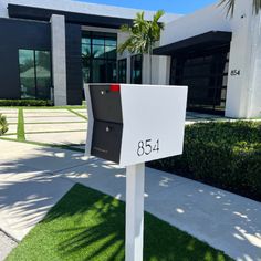 a mailbox sitting in front of a building with grass and palm trees around it