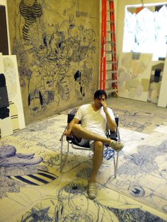 a man sitting on a chair in front of a drawing