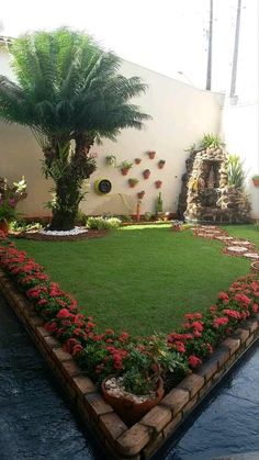 a lawn with red flowers and palm trees in the center is surrounded by brick edgings