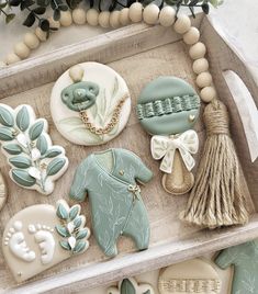 decorated cookies are displayed in a tray on a table with greenery and beads around them