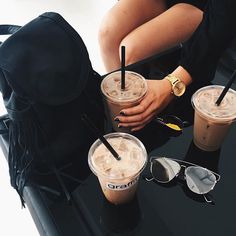 two people are sitting at a table with drinks in their hands and one is holding a backpack