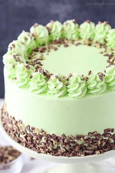 a cake with green frosting and chocolate sprinkles on the top is sitting on a plate