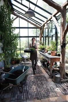 a woman walking through a greenhouse filled with potted plants