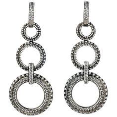 Dance the night away in this trending Estate Diamond 18K Gold triple Circle Dangle Drop Earrings!  These earrings are crafted in 18-karat white gold with fashionable black rhodium plating.  There are various sparkling genuine diamonds, round cut, white pave set round diamonds, totaling approximately 7.00 carats with G-H color and VS clarity.  They are delicately set in six circle motifs and four vertical gold bar links.  The circle designs range from 13 to 28 millimeters in width and the backings are hinge style for pierced ears. Weight: 20.8 Grams Measurements: 70 mm Length x 28 mm Width Condition: Excellent Signed: Daniel K Accompanied by a professional appraisal document. Round Diamond Stud Earrings, Daniel K, Womens Earrings, Diamond Dangle Earrings, Circle Diamond, Brown Diamond, Earrings Black, Black Rhodium, Fine Earrings