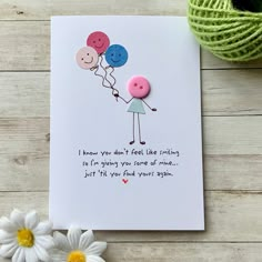 a greeting card with two buttons attached to the front of it, and a flower next to it