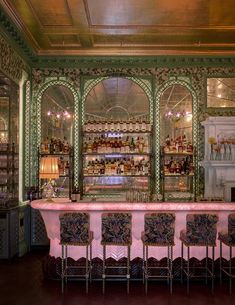 an ornately decorated bar with pink table cloths and chairs in front of it