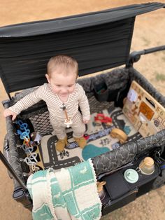 a baby in a stroller filled with toys and other things to play with on the ground