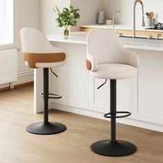 two white stools sitting in front of a kitchen counter