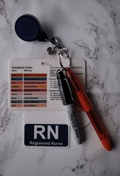 a red pen is sitting next to an identification card and keychain on a marble surface