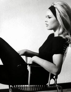 a black and white photo of a woman sitting in a chair with her legs crossed