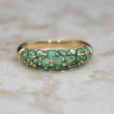 a gold ring with green stones on it