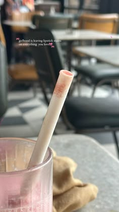 a glass filled with pink liquid sitting on top of a table next to a chair