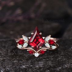 a close up of a ring with a red and white stone in the center on a rock