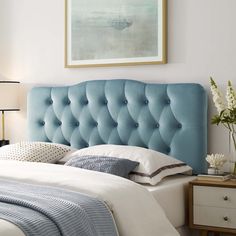 a bedroom with a blue headboard and white bedding