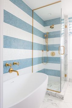 a white bath tub sitting next to a walk in shower with blue and white tiles