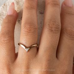 a woman's hand with a gold ring on top of her finger and a diamond in the middle