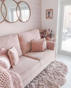 a living room with pink furniture and mirrors on the wall