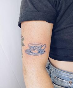 a woman with a tattoo on her arm has a cup and saucer in it