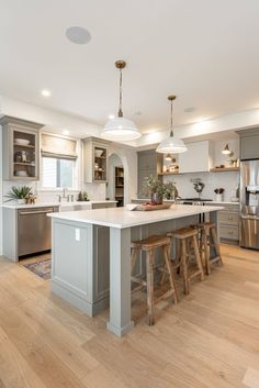 a large kitchen with an island and two stools in the middle of the room