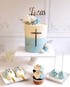 a cake and cupcakes are sitting on a white table with blue decorating