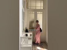 a woman in a pink dress is standing at the entrance to a room with an open door