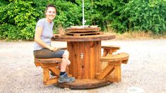 a woman sitting at a picnic table made out of wood