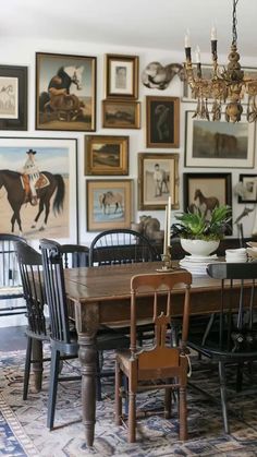 a dining room table with chairs and pictures on the wall behind it, including a horse