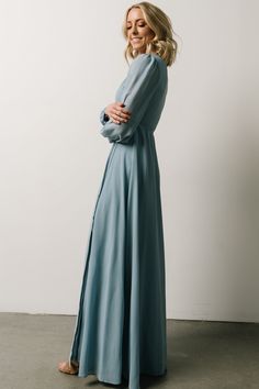 Dusty blue hue High-quality chiffon material True-wrap style Attached ties at waist Classy long sleeves Fabric buttons at sleeve cuffs Attached full lining 100% Polyester Trina is 5'6, cup size 32C, size 2 and is wearing size S Chiffon Maxi Dress With Sheer Long Sleeves, Blue Long Sleeve Chiffon Maxi Dress, Chic Light Blue Long Sleeve Maxi Dress, Flowy Long Sleeve Belted Maxi Dress, Blue Dresses With Belted Cuffs, Blue Fitted Dress With Belted Cuffs, Chic Blue Dress With Belted Cuffs, Elegant Blue Dresses With Belted Cuffs, Flowy Long Sleeve Dress With Tie Waist