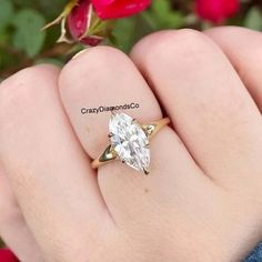 a woman's hand holding a ring with a large diamond on the top and bottom