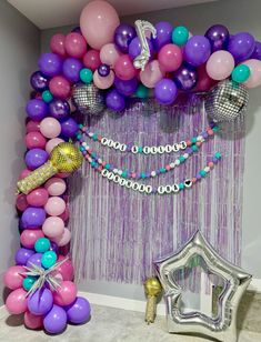 balloons and streamers decorate the entrance to a birthday party with purple, pink, and blue colors