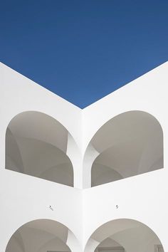 an empty white building with arches and blue sky in the backgrounnds