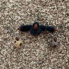 three small stuffed animals are on carpeted area with two keychains in the shape of gorillas