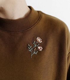 a close up of a person wearing a sweater with flowers embroidered on the back of it