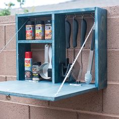 a blue shelf with utensils and other kitchen items hanging on it's side