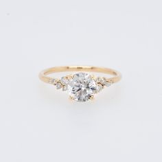 a gold engagement ring with an oval cut diamond in the center and three smaller round diamonds on each side